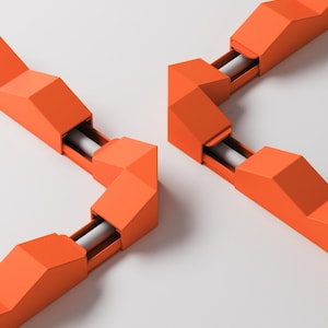 Op de afbeelding: Fel oranje modulaire railverlichtingscomponenten met geometrische, hoekige behuizingen. Deze segmenten verbinden zich tot een rigide, gefacetteerde structuur, waarbij witte cilindrische lichtbronnen in de oranje behuizing zichtbaar zijn.