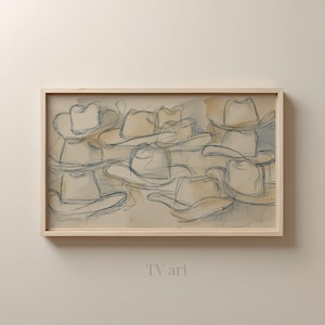 Peut inclure: Une œuvre d'art encadrée représentant une esquisse de plusieurs chapeaux de cow-boy dans une palette de couleurs neutres. Les chapeaux sont soulignés en bleu foncé, avec un fond lavé à l'aquarelle beige et bleu clair. Le texte "TV art" est en bas.