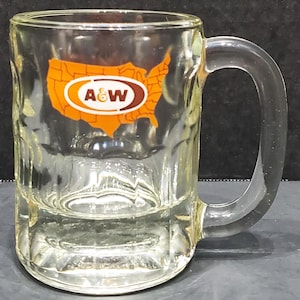 May include: A clear glass mug with a handle. The mug has an orange and brown A&W logo with a map of the United States in the background.