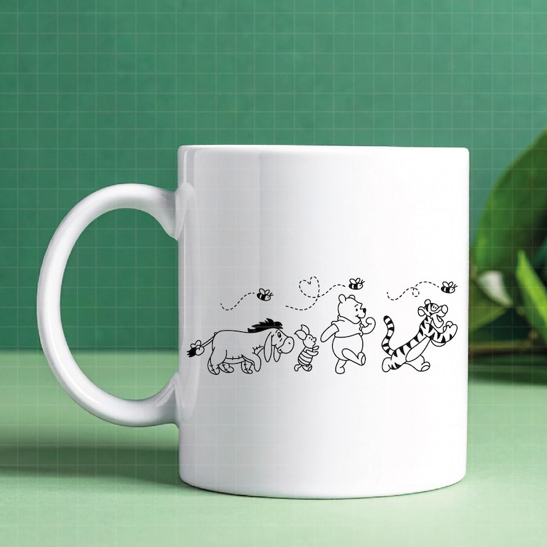 Puede incluir: Taza de cer&aacute;mica blanca con una ilustraci&oacute;n en blanco y negro de Winnie the Pooh y sus amigos. El dise&ntilde;o incluye a &Iacute;gor, Piglet, Winnie the Pooh y Tigger, con abejas y l&iacute;neas punteadas.