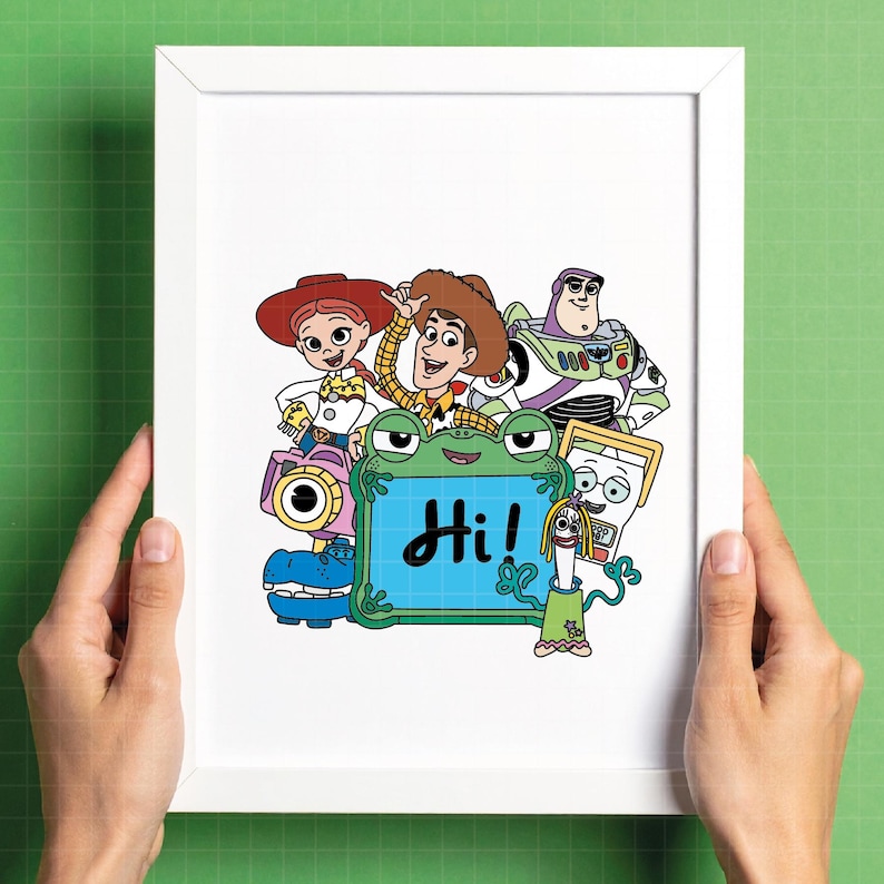 May include: A framed print featuring cartoon characters from the Toy Story franchise. The characters include Woody, Buzz Lightyear, Jessie, and others. A green frog-shaped sign displays the word "Hi!" in blue. The print is held in a white frame.