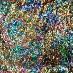 Pode incluir: Um close-up de um tecido iridescente coberto de lantejoulas. As lantejoulas são em tons de dourado, azul, verde e roxo.
