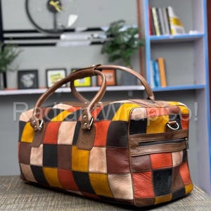 May include: A patchwork leather duffel bag with a variety of colors including brown, orange, yellow, and black. The bag has brown leather handles and a zipper closure. The text "Radiant Wings" is visible on the bag.