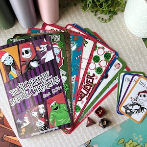 May include: A collection of colorful cards and dice featuring characters and themes from "The Nightmare Before Christmas." The cards display various designs, including character illustrations and the text "BELIEVER." The dice are red and brown.