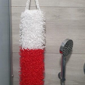 Puede incluir: Un puff de baño blanco y rojo con un asa de bucle colgando de un gancho en un baño.