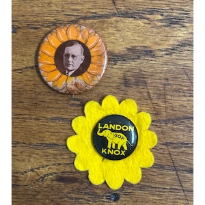 May include: Two circular political campaign buttons. The top button features a portrait of a man in a suit surrounded by orange sunflower petals. The bottom button is black with a yellow elephant graphic and the text LANDON GOP KNOX.