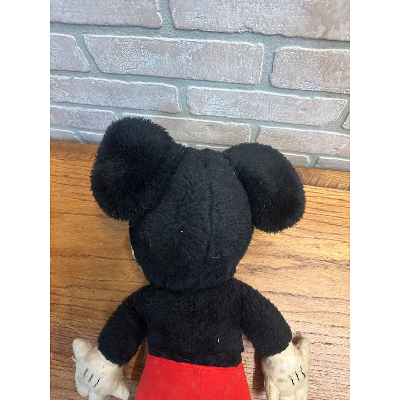 May include: Vintage Mickey Mouse soft toy. The toy features a black head with large ears, a black body, red shorts, and white gloves. The toy is made of soft, plush material and is a classic Disney collectible.