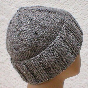 May include: A grey knitted beanie with a folded brim. The beanie is made of a soft, textured yarn.