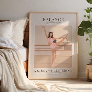 May include: A framed art print featuring a ballet dancer in a pink outfit, striking a pose in a dance studio. The print has the words "BALANCE équilibre et axe" at the top and "A STUDY OF CENTERING" at the bottom. The artwork is displayed near a bed.