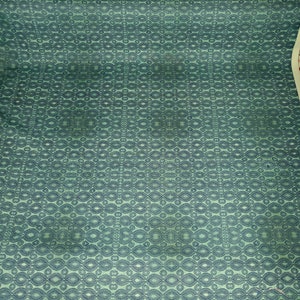 May include: A green fabric with a repeating pattern of dark blue ovals and circles.