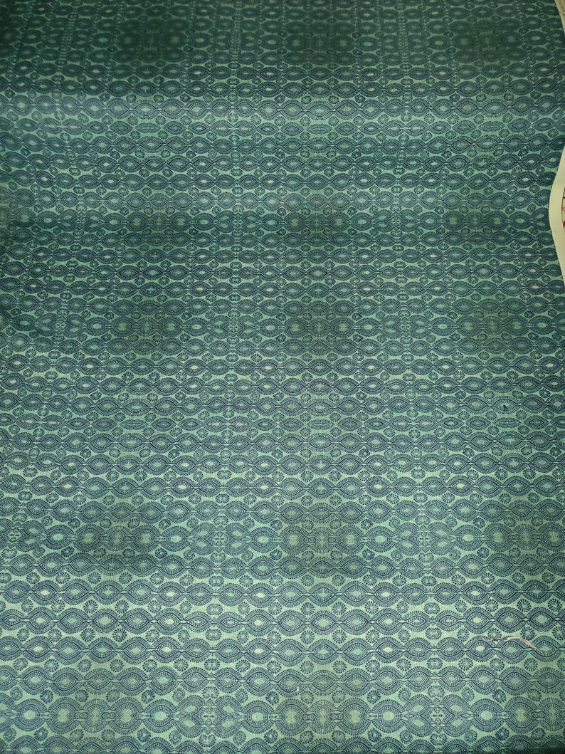 May include: A green fabric with a repeating pattern of dark blue ovals and circles.