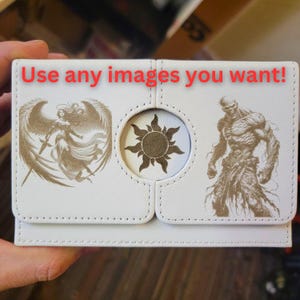 May include: White leather box with three compartments. The left compartment has a golden image of a woman with wings and a sword. The middle compartment has a golden sun image. The right compartment has a golden image of a muscular man with a beard.