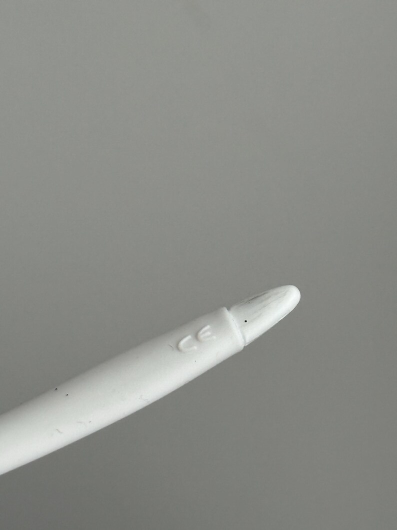 May include: A white stylus with a rounded tip and the letters "CE" printed on the side. The stylus is designed for use with a touchscreen device and is shown against a gray background.