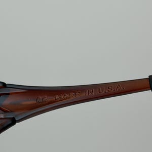 K&ouml;nnte beinhalten: Nahaufnahme des B&uuml;gels einer braunen Sonnenbrille. Der Text "MADE IN U.S.A." ist auf dem B&uuml;gel aufgedruckt. Die Sonnenbrille hat ein dunkelbraunes Schildpattmuster.