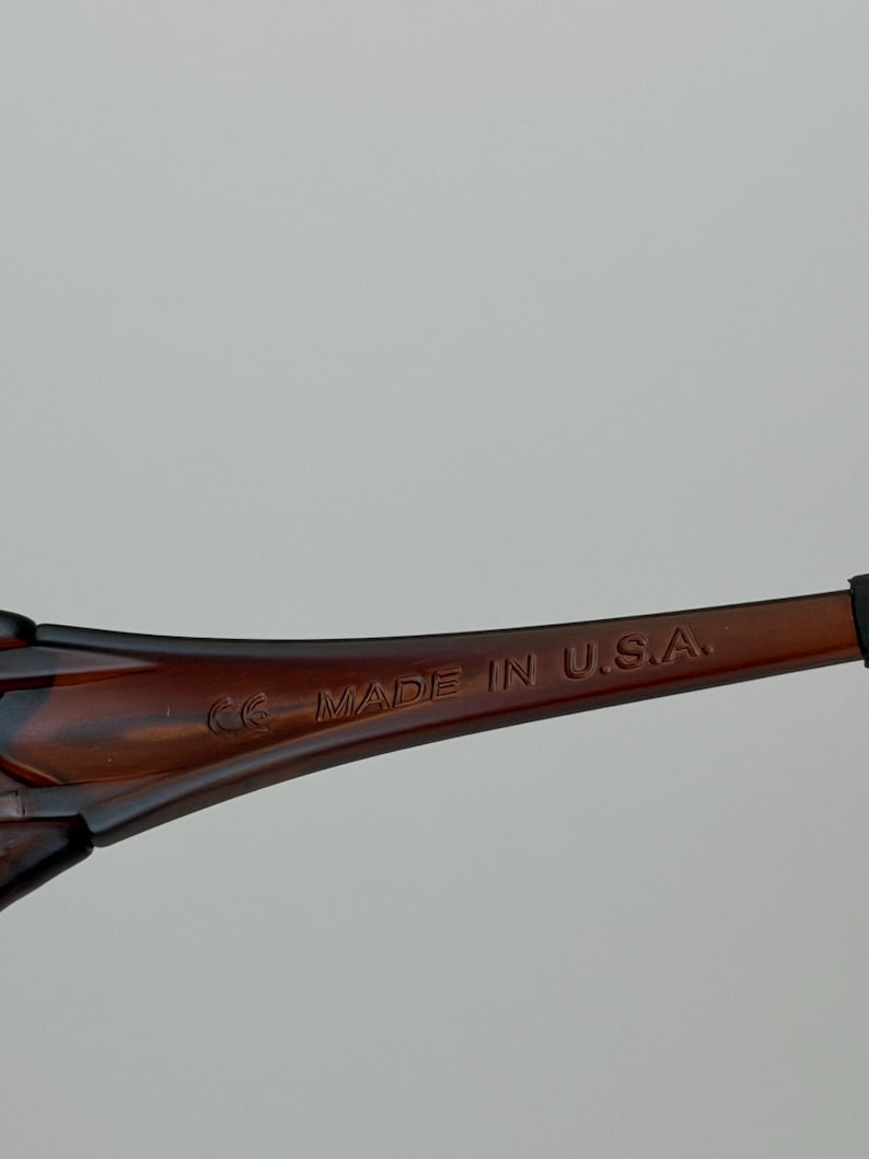 K&ouml;nnte beinhalten: Nahaufnahme des B&uuml;gels einer braunen Sonnenbrille. Der Text "MADE IN U.S.A." ist auf dem B&uuml;gel aufgedruckt. Die Sonnenbrille hat ein dunkelbraunes Schildpattmuster.