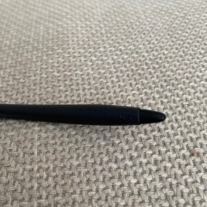 Puede incluir: Un l&aacute;piz &oacute;ptico negro con punta redondeada. El l&aacute;piz &oacute;ptico est&aacute; sobre una superficie beige texturizada. El l&aacute;piz &oacute;ptico tiene las letras "CG" impresas en el lateral.