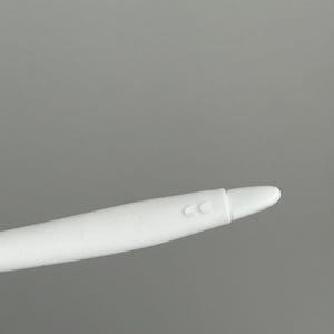May include: A white stylus with a rounded tip. The stylus has a smooth, matte finish and a slight curve. The letters "CC" are printed on the side of the stylus.