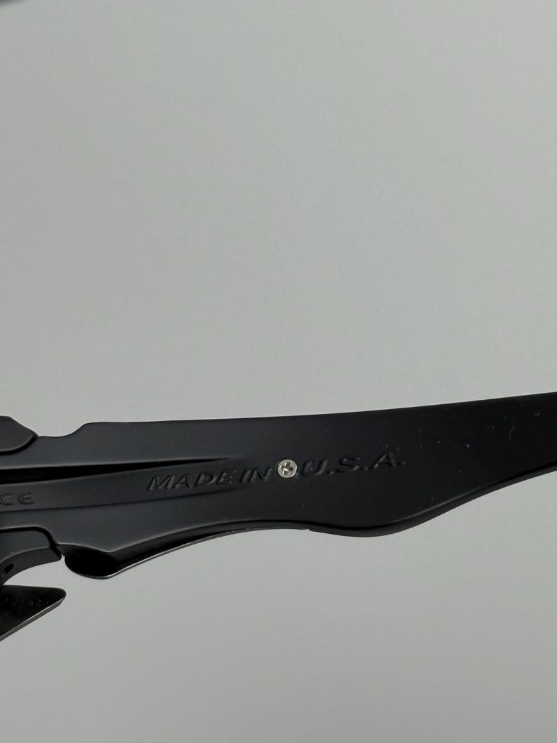 May include: Close-up of a black object with the text "MADE IN U.S.A." printed on it. The object has a sleek, modern design and appears to be made of a durable material. The background is a solid, neutral gray.