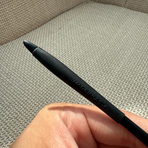 May include: A black stylus with a rounded tip. The stylus is marked with the text "MADE IN U.S.A." The stylus is held in a hand.