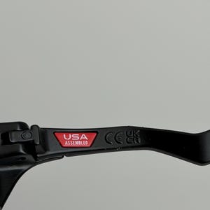 May include: Black lever with the text "USA Assembled" in a red rectangle. The lever also has the CE mark. The lever is likely a component of a bicycle or motorcycle.