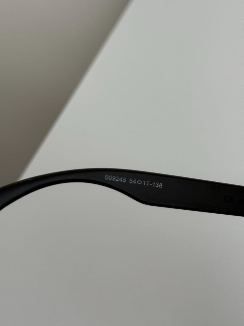 May include: Black eyeglasses with the text "009245 54017-138" printed on the inside of the arm. The glasses are set against a white background.