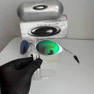 May include: Silver-framed sunglasses with green mirrored lenses and blue mirrored lenses. The sunglasses are displayed with a silver case and a box with the text "SCIENCE AND ART".