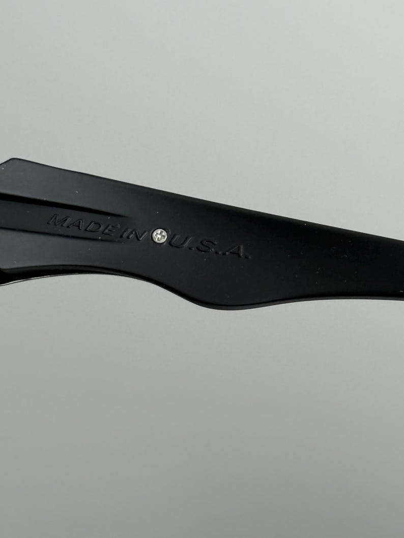 May include: Close-up of a black object with the text "MADE IN U.S.A." printed in white. The object has a curved shape and is set against a light gray background.