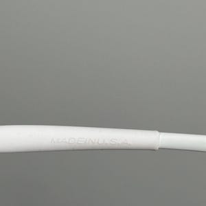 May include: Close-up of a white object with the text "MADE IN U.S.A." printed on it. The object is against a gray background.