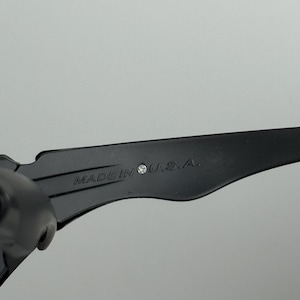 May include: Close-up of a black object with the text "MADE IN U.S.A." printed on it. The object has a sleek, modern design and appears to be made of a durable material. The text is in a clear, easy-to-read font.