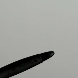 May include: A black stylus with a rounded tip. The stylus has a matte finish and a curved design. The letters "CE" are printed on the side of the stylus.