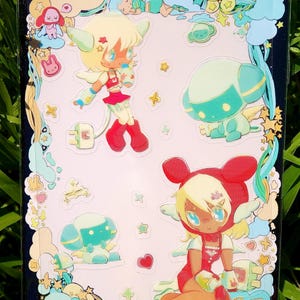 May include: A sheet of stickers featuring several cartoon characters with angel wings, in red, blue, and yellow. The stickers have a glossy finish and are surrounded by a black border with stars and clouds.