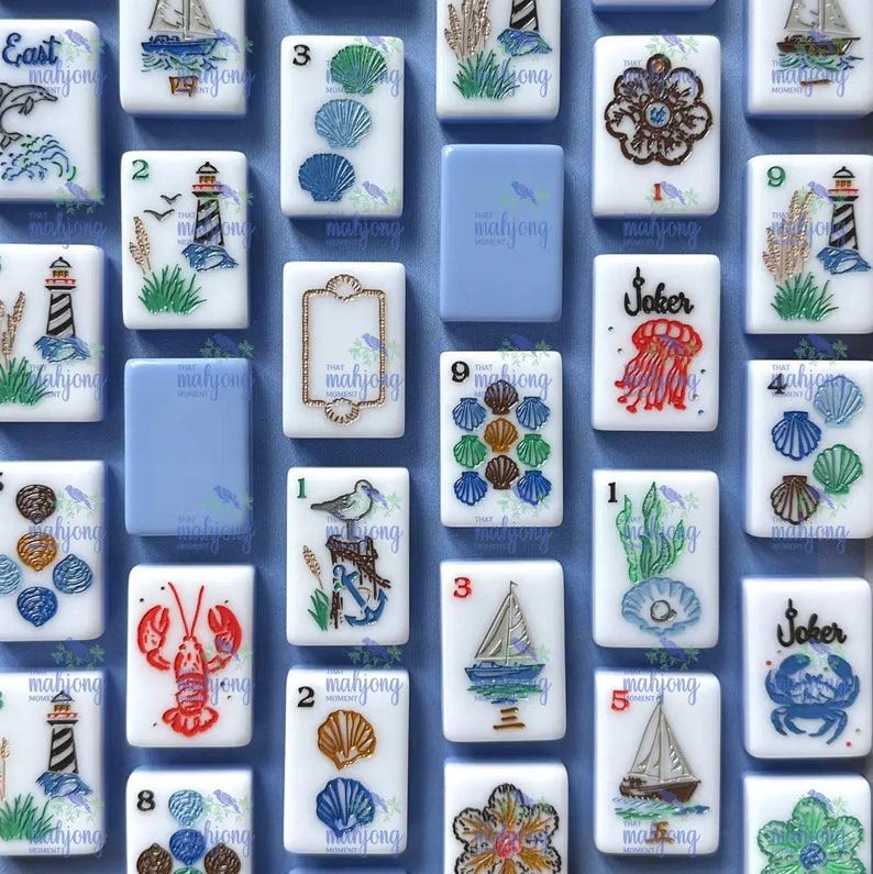 May include: A collection of white Mahjong tiles with nautical-themed illustrations. The tiles feature images of sailboats, seashells, lighthouses, and marine life, with numbers and the word "Joker" on some. The background is a light blue.