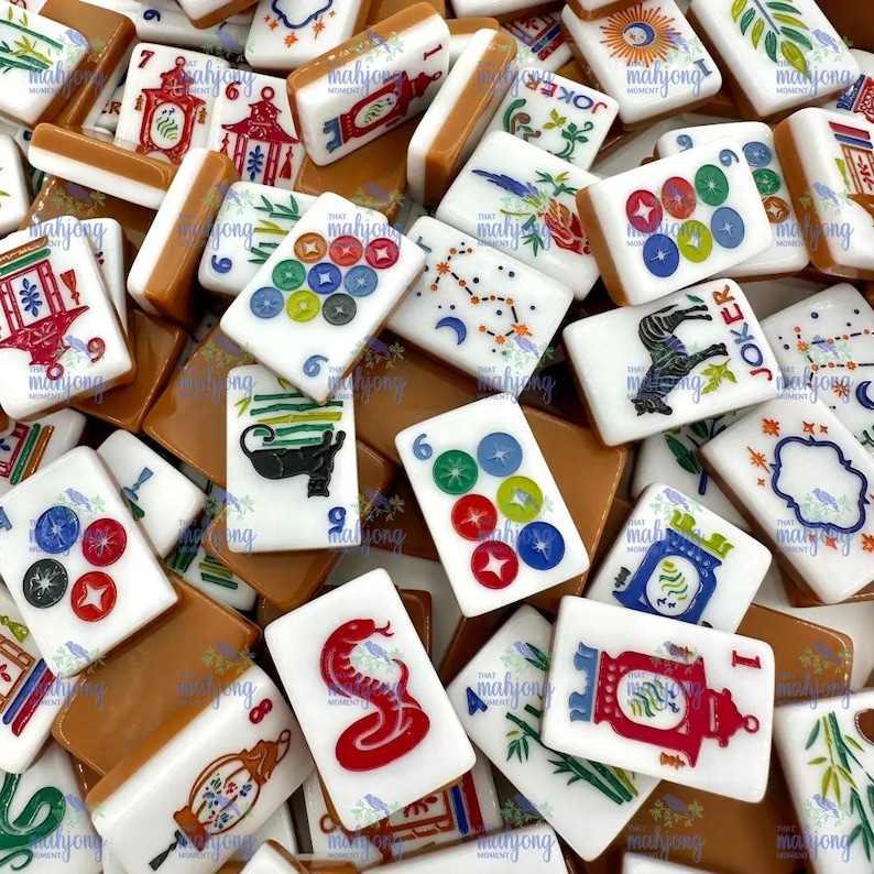 May include: A collection of Mahjong tiles with various symbols and designs. The tiles feature red, green, blue, and white colors, with some displaying numbers, illustrations, and the word "Joker". The tiles are arranged in a pile, showcasing the diverse artwork.