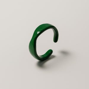 May include: A vibrant, emerald green ring with a flowing, organic form. The ring is likely made from a solid material, such as resin or ceramic. The design is minimalist and contemporary, with a smooth, reflective surface.