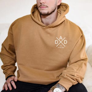 a man sitting on a couch wearing a brown hoodie
