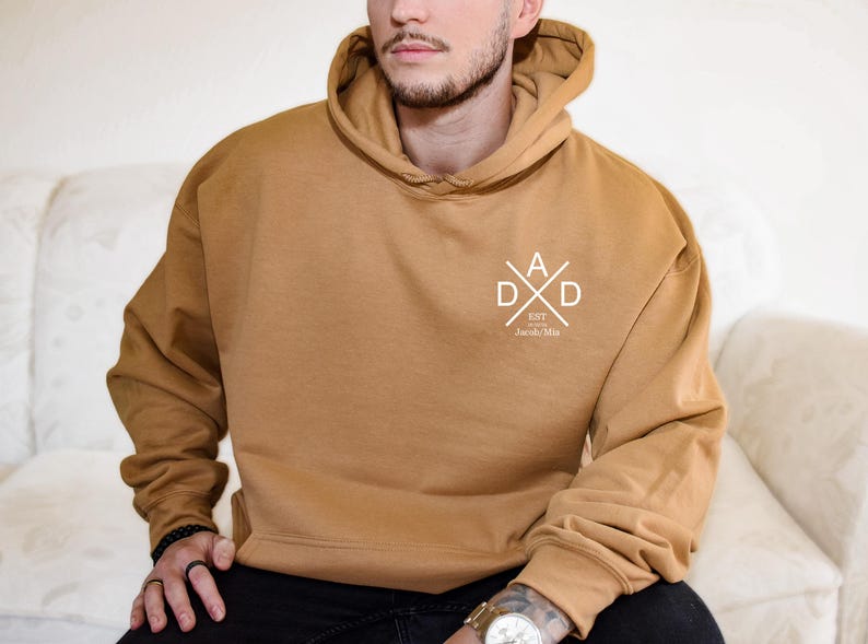 a man sitting on a couch wearing a brown hoodie