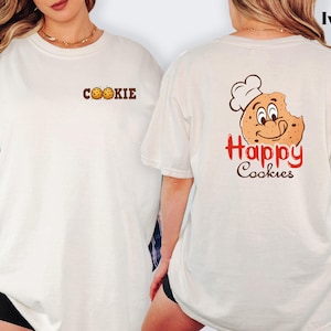 A woman wearing a white t-shirt with a cookie and happy cookie graphic on the back.