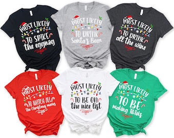 May include: Six short-sleeved t-shirts with Christmas-themed text. The shirts are black, gray, dark gray, red, white, and green. Each shirt has the phrase "Most Likely" above a different Christmas-related activity, such as "to spike the eggnog."
