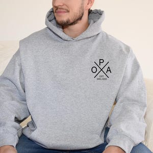 a man sitting on a couch wearing a grey hoodie