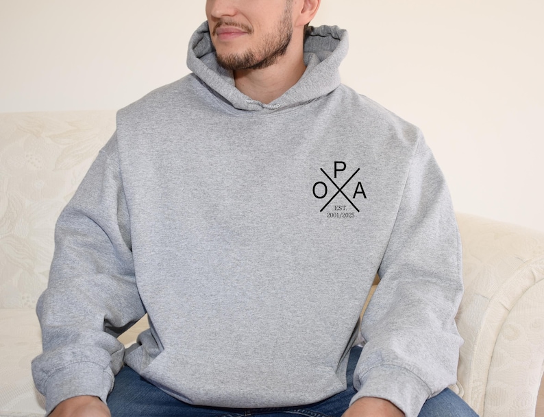 a man sitting on a couch wearing a grey hoodie