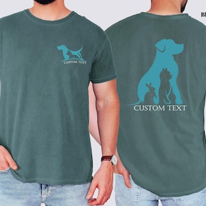 A man wearing a green t-shirt with a graphic design of a dog and a cat on the front and back.