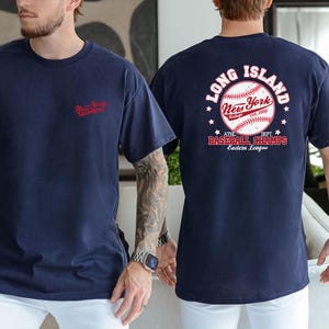 two men wearing navy blue t-shirts with the text "Long Island New York" and "At the 2013 Baseball Champs" printed on them.