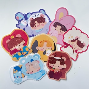 Puede incluir: Una colección de pegatinas de dibujos animados coloridos con personajes con disfraces de animales, como un oso, un conejo y una oveja. Las pegatinas tienen un diseño lindo y caprichoso con colores suaves e ilustraciones detalladas. Perfecto para decorar cuadernos.