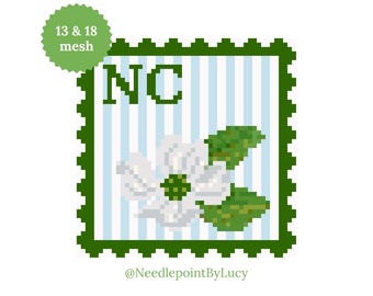 May include: A pixelated design featuring a white dogwood flower, green leaves, and the letters "NC" on a light blue striped background. The design is framed by a green border and includes the text "13 & 18 mesh" and the artist's name.