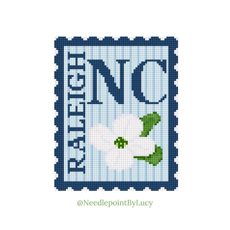 May include: A cross-stitch design of a postage stamp featuring "NC" in navy blue, with "RALEIGH" vertically on the left. A white dogwood flower with green leaves is in the center. The background is light blue.