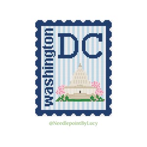 May include: A cross-stitch design of a postage stamp featuring the Washington, D.C. Capitol building. The stamp has a blue border and the text "Washington" and "DC". Pink flowers and green grass are at the base of the building.