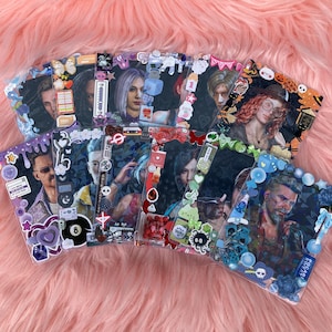 Puede incluir: Una colección de tarjetas fotográficas decoradas con varios retratos. Cada tarjeta tiene un borde único con pegatinas, abalorios y adornos. Las tarjetas muestran una variedad de colores y temas, algunos incluyen texto y elementos decorativos.