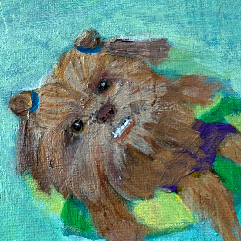May include: An oil painting of a small, brown dog with a smiling expression. The dog has blue accents on its ears and is set against a light blue and green background. The artwork has visible brushstrokes.