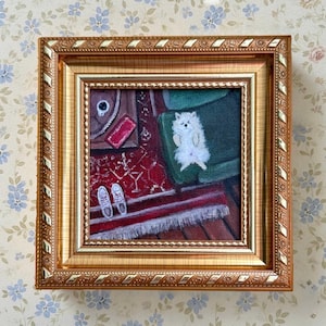 Puede incluir: Pintura enmarcada que representa un perro blanco tumbado en una silla verde. La pintura tiene un marco dorado y muestra una alfombra roja con zapatillas blancas. El fondo tiene un papel pintado floral.