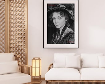 May include: Black and white framed portrait of a woman wearing a large hat with a dark dress. The portrait is in a black frame and hangs on a white wall. The room has a modern design with wooden furniture.